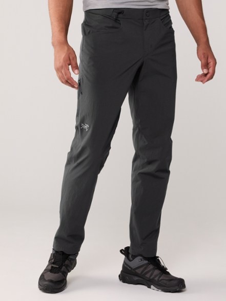 Arc'teryx Konseal performance pants shown on a rocky climbing surface, demonstrating flexibility.
