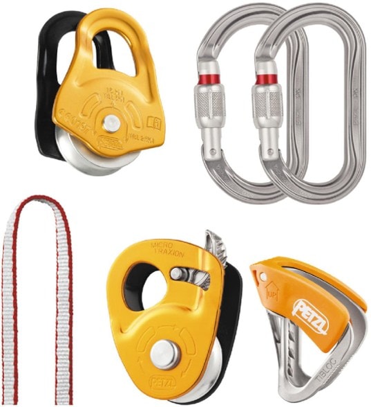 Petzl Crevasse Rescue Kit components displayed on a rugged terrain, showcasing the Micro Traxion pulley and carabiners.